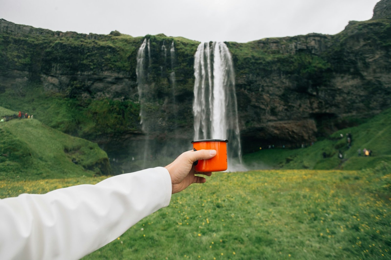 Man hold cup under waterfall in iceland